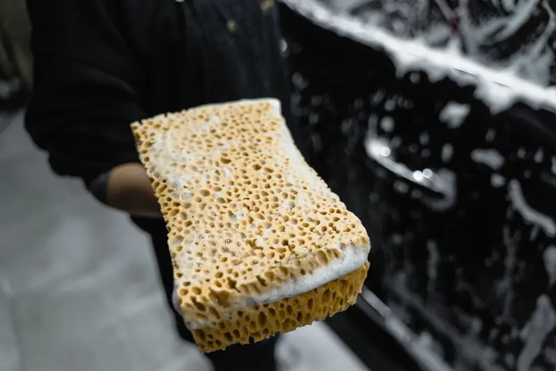 A soapy wash mitt beside a car