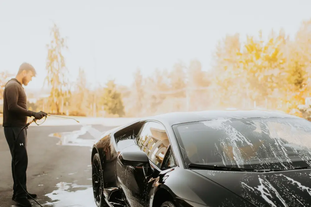 Foam running down a black sports car during a wash